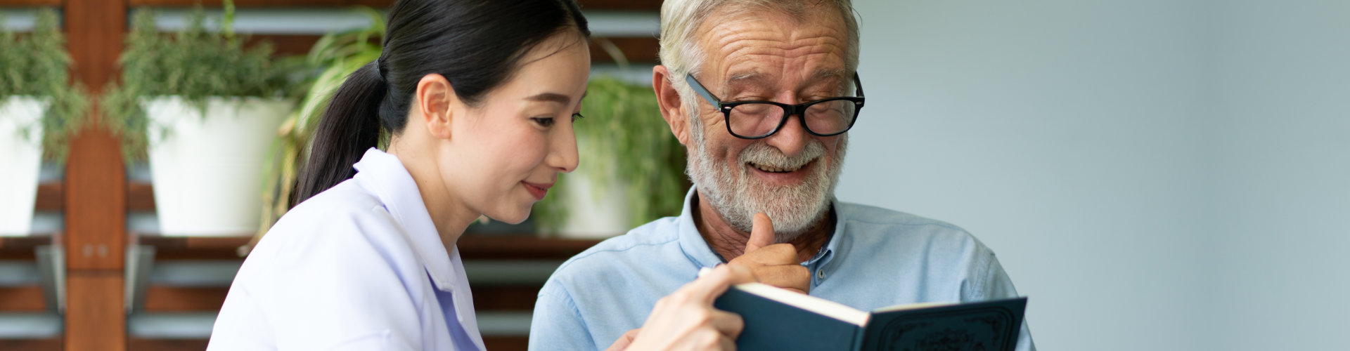 nurse and elderly man reading book